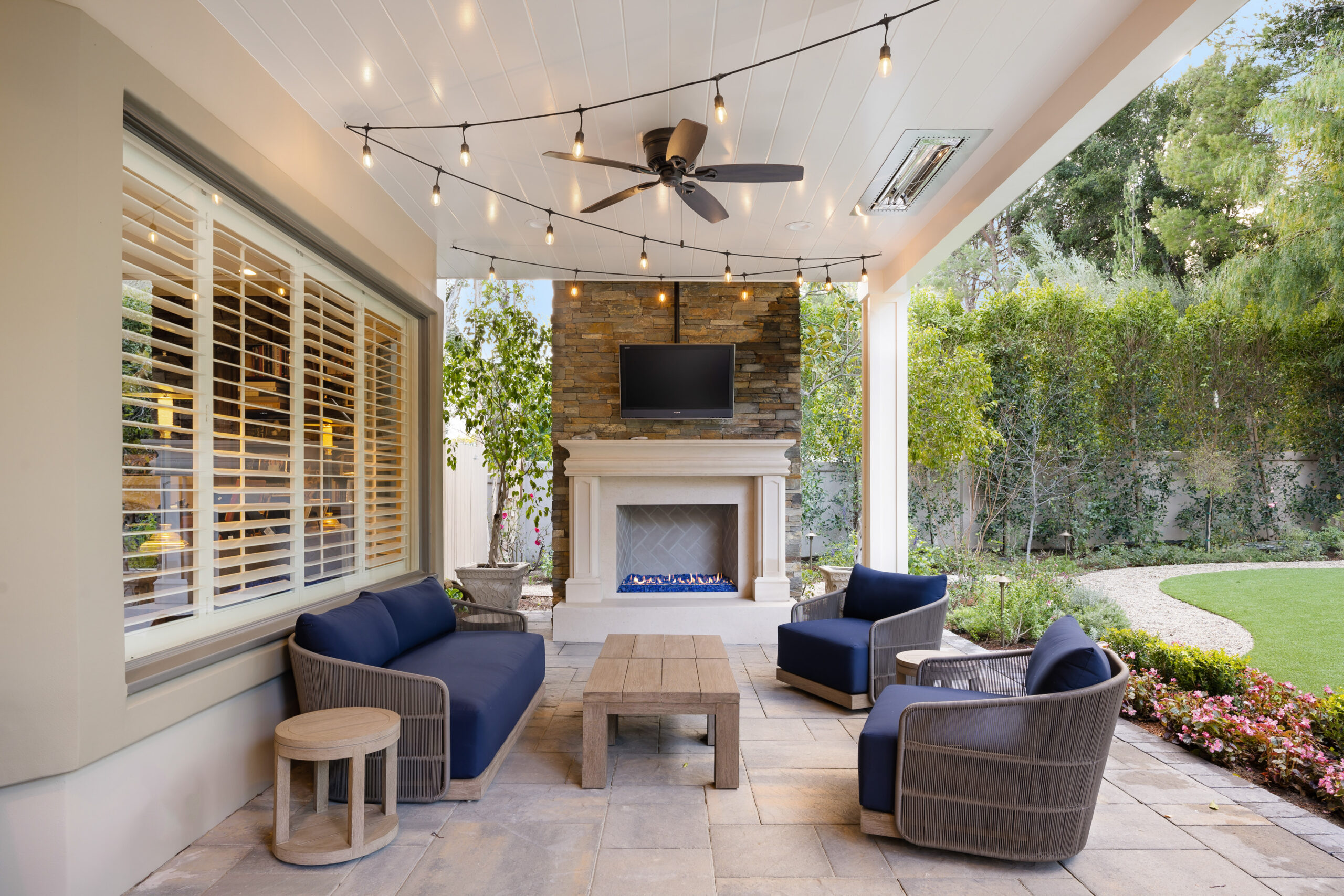 An outdoor living space featuring Outdoor Bistro & Café Lighting hung across the ceiling,