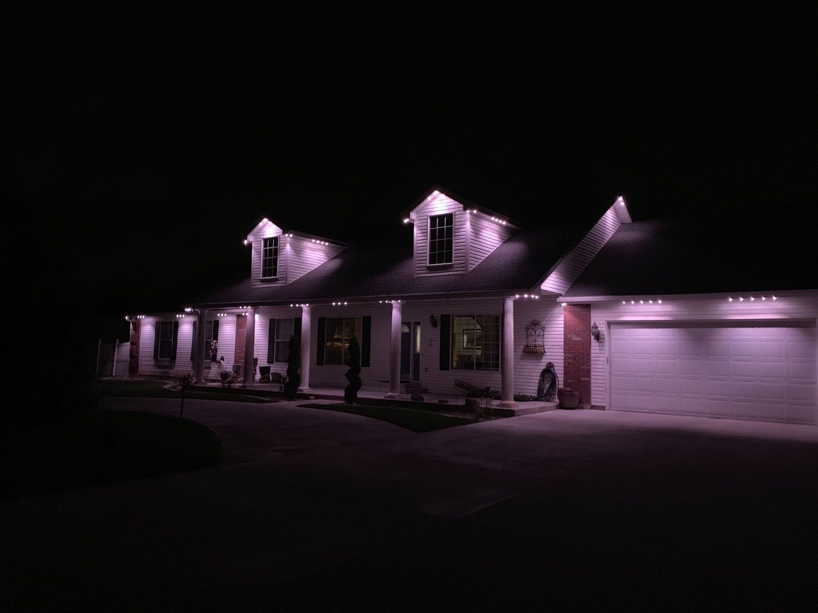 A large house elegantly illuminated with white Exterior Accent Lighting along the roofline, enhancing its architectural details