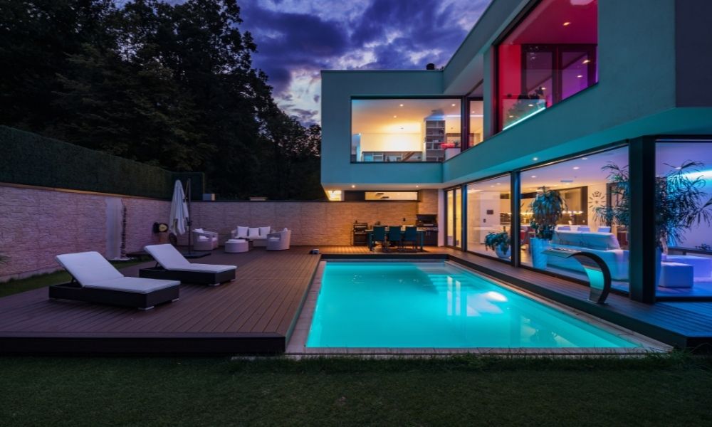 Exterior of a modern villa at night, featuring a swimming pool illuminated with blue light.