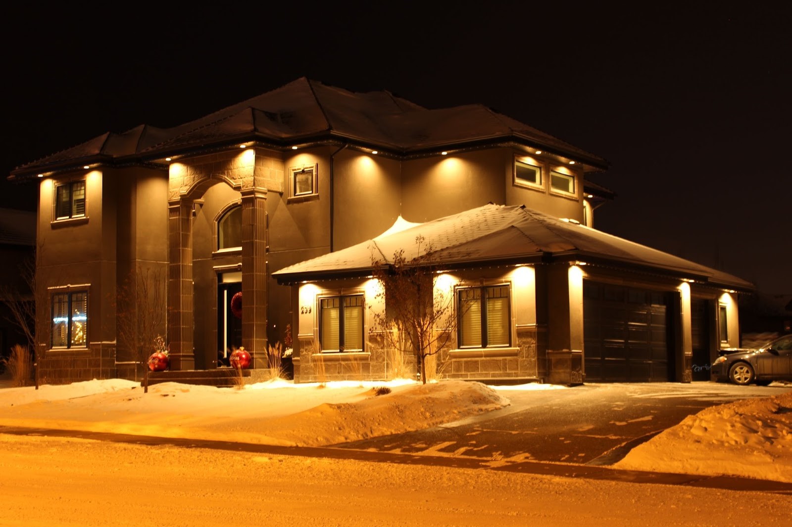 A modern house covered in snow, beautifully illuminated by warm Outdoor LED Soffit Lighting.