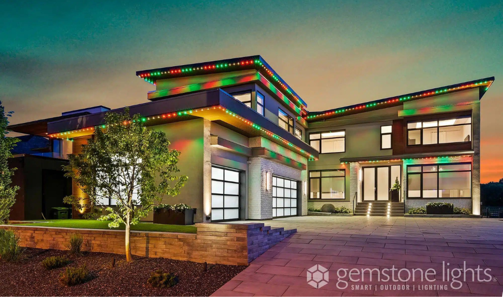 A modern home illuminated with customizable red and green permanent holiday lights along the roofline in color green warm white and red.