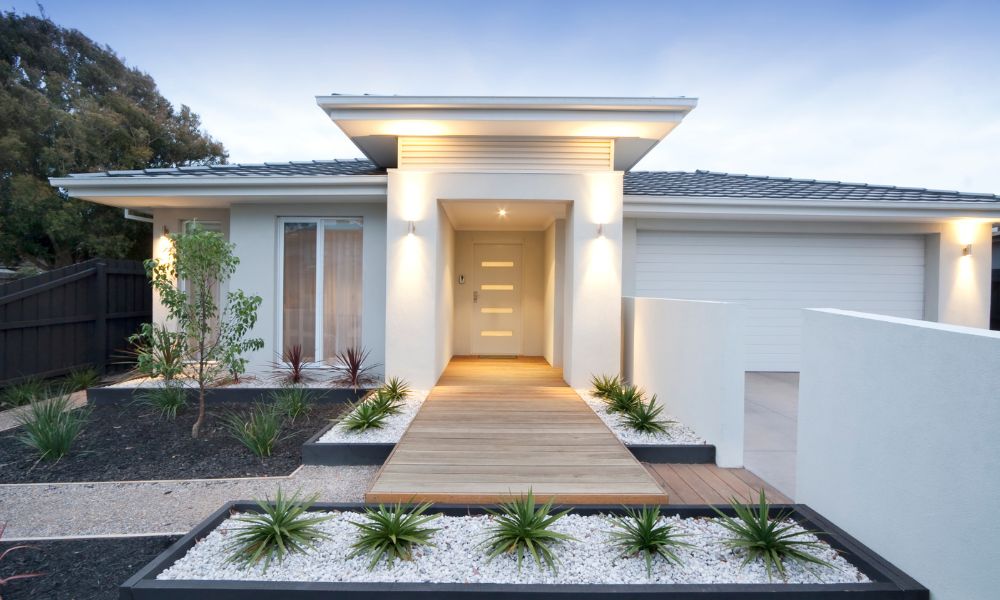 A sleek white modern house with architectural lighting that accentuates the entrance.
