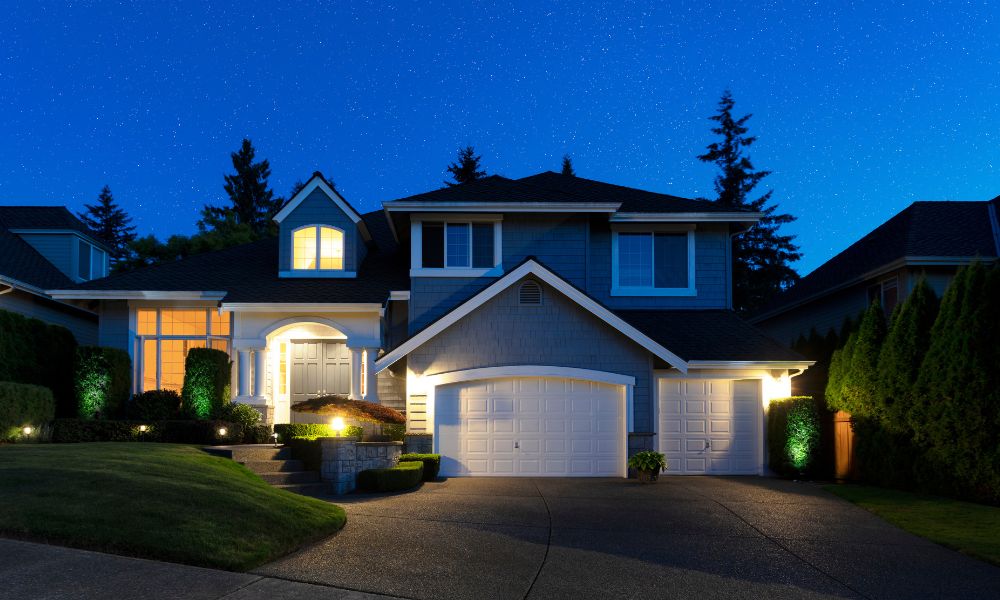 A suburban house beautifully illuminated at night by outdoor smart lights, casting a warm glow that highlights its architectural details.
