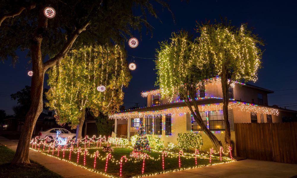 house beautifully decorated with Christmas lights, featuring permanent lights along the roofline and glowing candy cane lights adorning the garden.