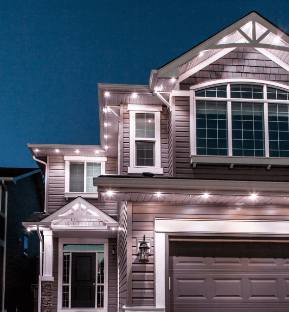 Exterior of a house at night, illuminated by Astoria Lighting. These lights are installed along the roofline and architectural features, highlighting the shape of the house.