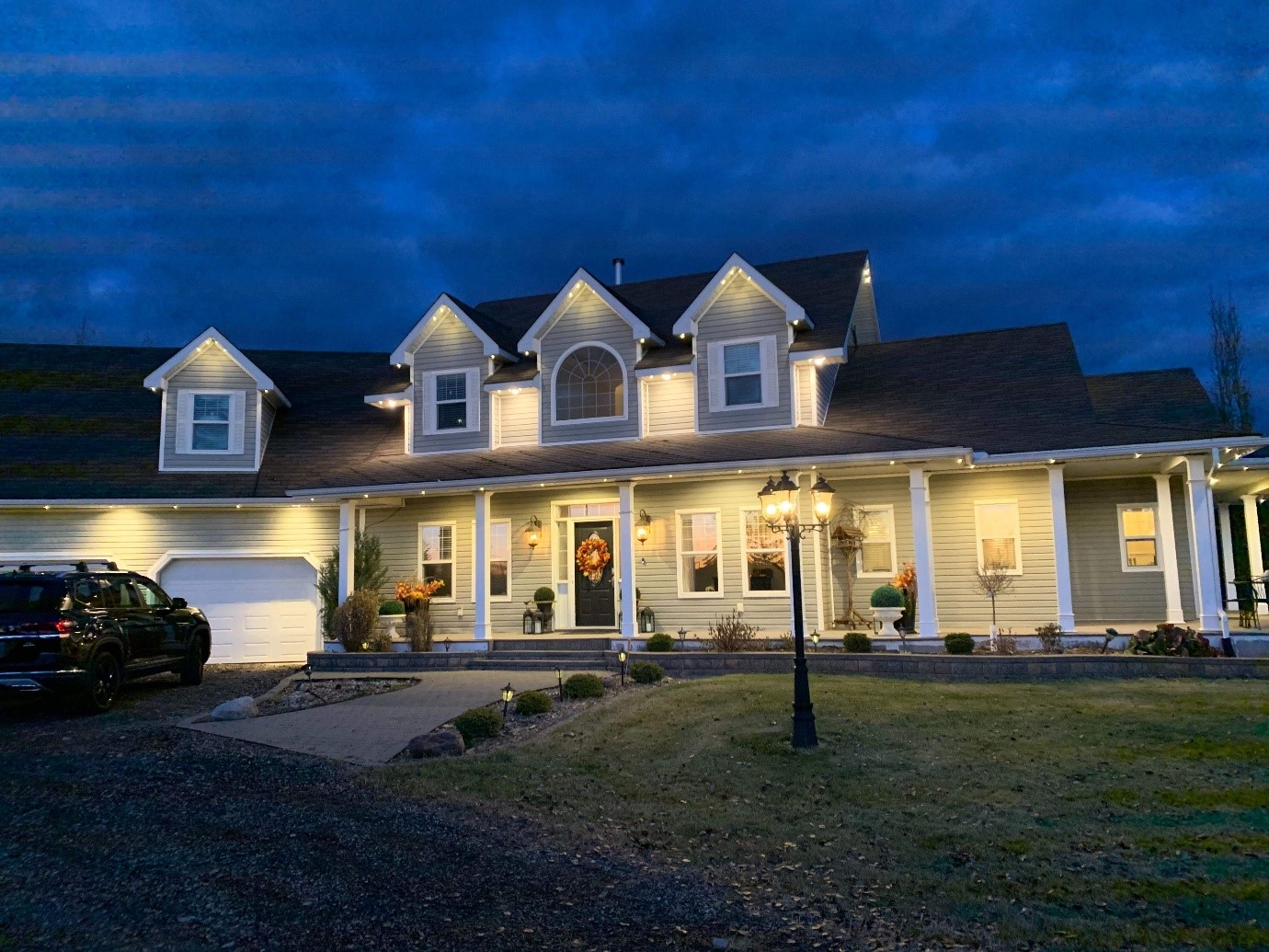 modern large house with warm exterior lighting elegantly illuminating the front facade at night, highlighting its architectural details and creating a welcoming ambiance.