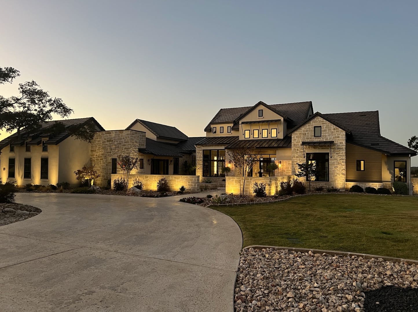 A well-lit, luxurious house at dusk, and strategically placed lighting that highlights its architectural details.