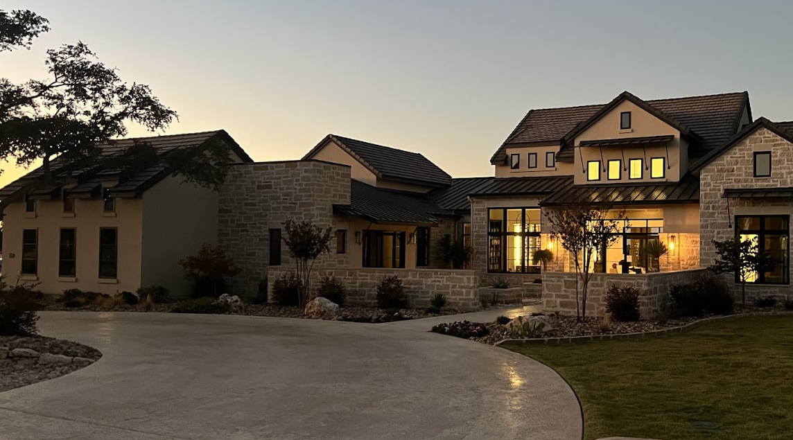 A well-lit, luxurious house at dusk, and strategically placed lighting that highlights its architectural details.