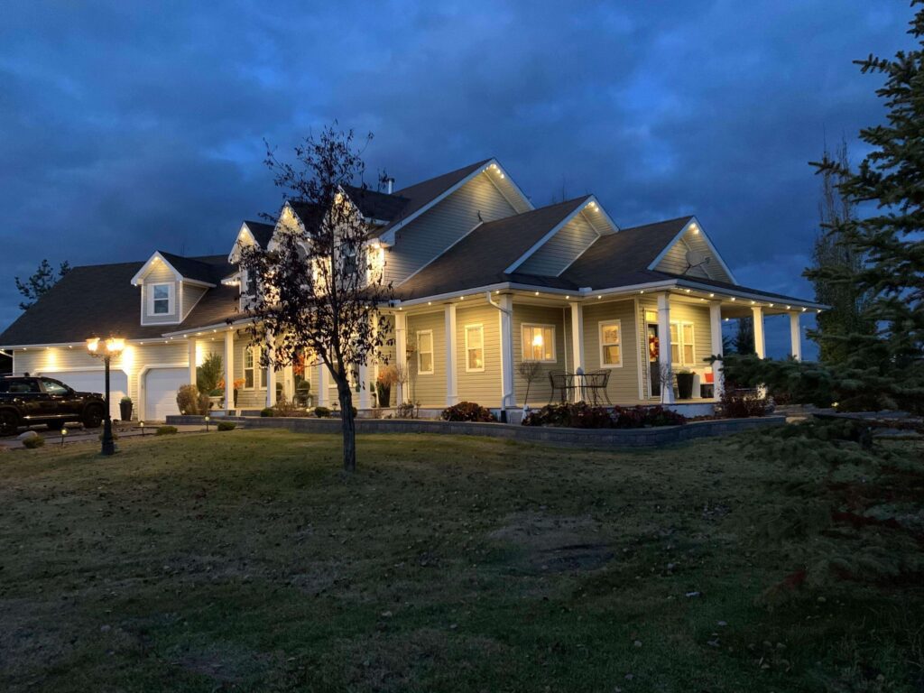 Two-story vinyl home showcasing Astoria’s signature permanent lighting system installed in the soffit, displaying warm white light that highlights the front and side entryways as well as the garage for an elegant, cohesive look.