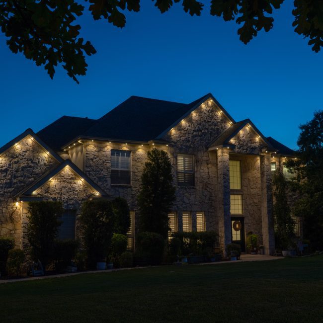 Luxury organic stone house featuring Astoria permanent lighting system along soffit line.