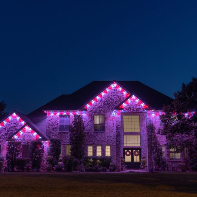 Luxury organic stone house featuring Astoria permanent lighting system along soffit line displaying valentine theme pink and white color pattern.