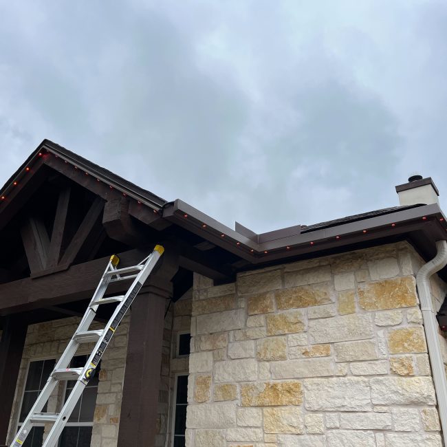 Stone exterior home featuring Astoria’s closed-track permanent lighting system along the soffit line, blending seamlessly with the home’s design and color palette.