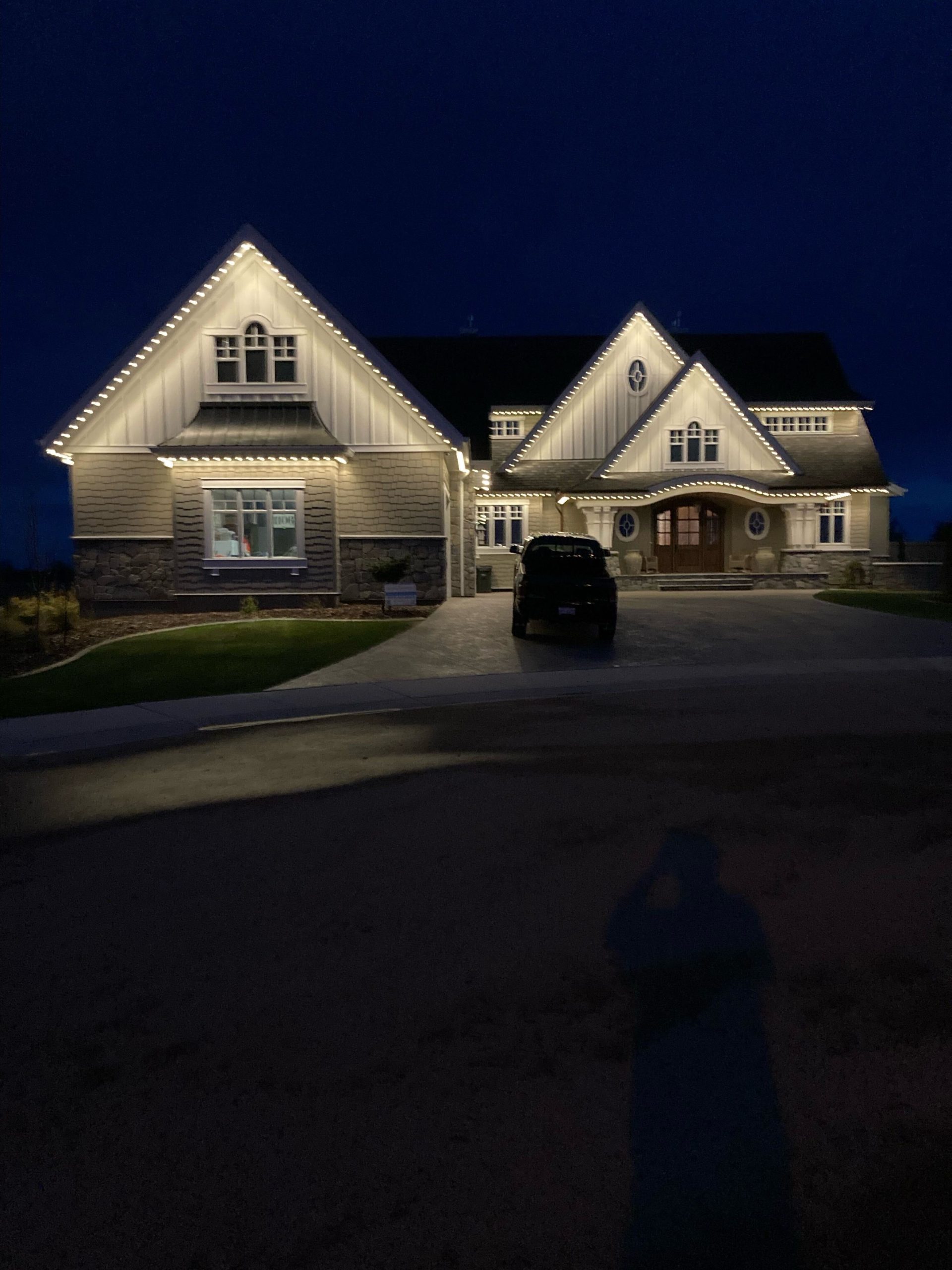 Residential home featuring Astoria permanent holiday lights installed along soffit line under night sky.